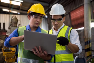 Dois trabalhadores em uma fábrica utilizando um tablet representando o que é OEE