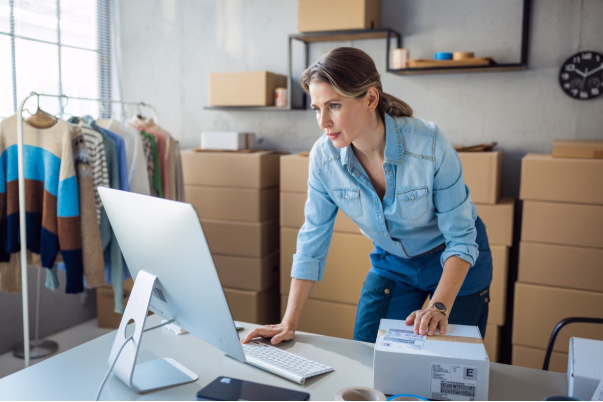 Uma mulher de blusa azul mexendo no computador representando desenvolvimento de software para pequenas empresas