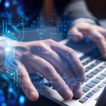 Empresário digitando em um notebook, com um holograma de circuito eletrônico azul sobreposto às mãos, simbolizando tecnologia e transformação digital.