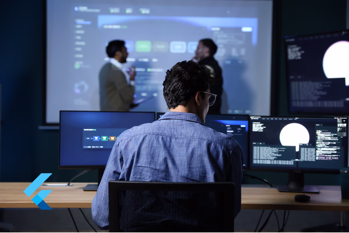 Developer working at multiple monitors displaying code and dashboards, with the Flutter logo in the foreground, representing a team migrating a native app to Flutter