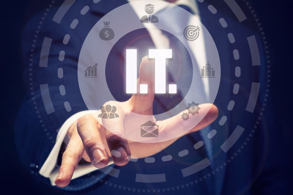 Businessman in a suit pointing at the text "I.T." on a digital panel with technology, management, and business icons, representing the top IT areas for 2027.