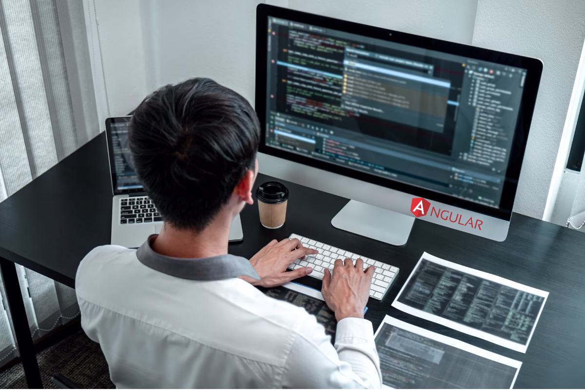 Angular developer working on code on a computer screen, with the Angular logo in the background.