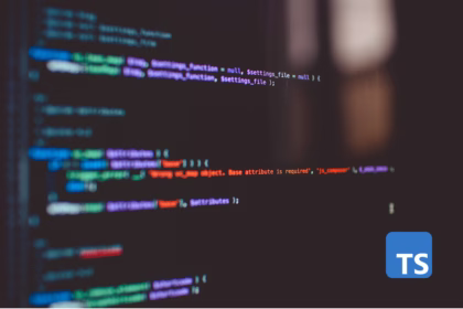 Tela de computador desfocada exibindo linhas de código com o logo do TypeScript (TS) em destaque no canto inferior direito.