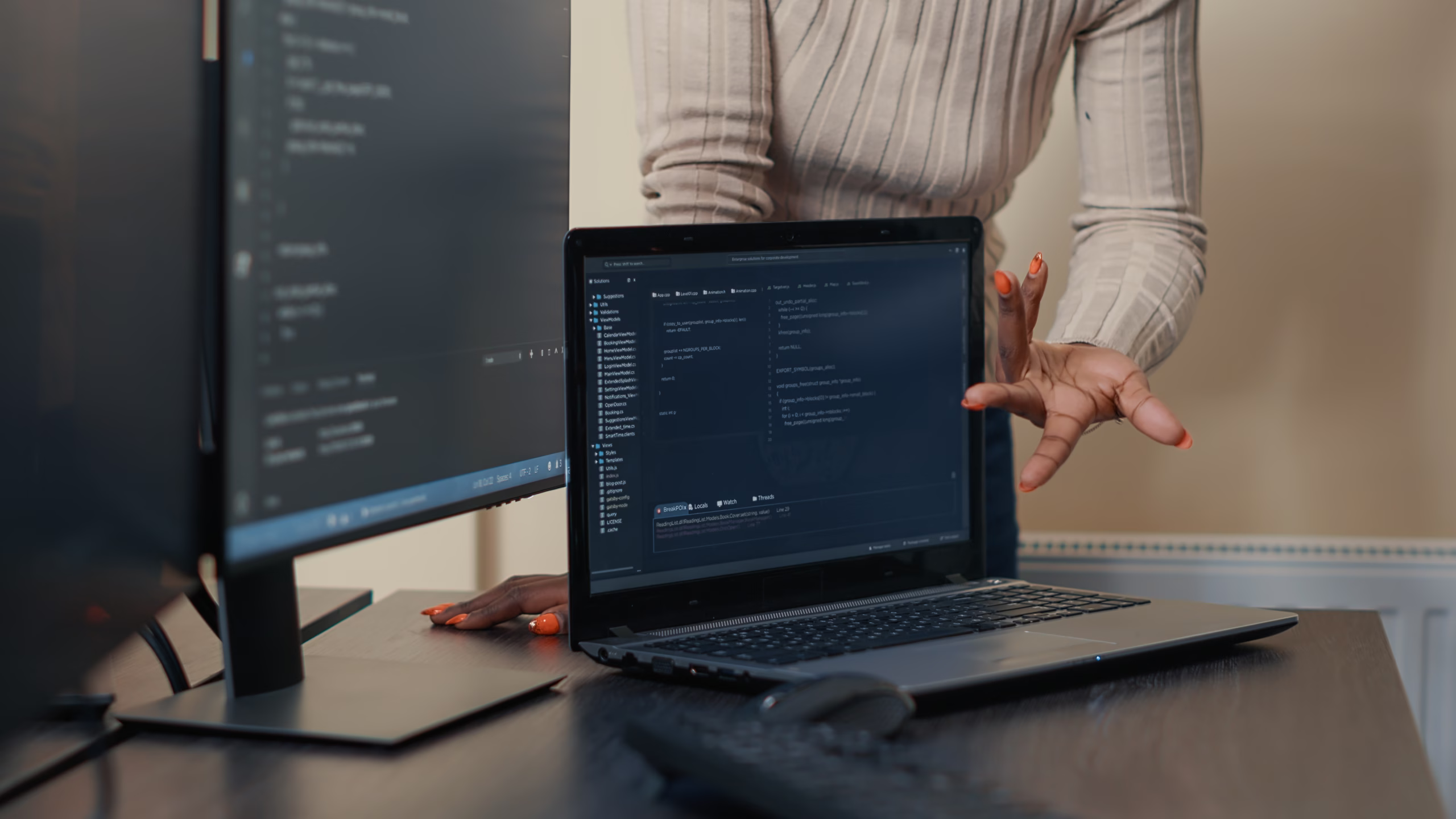 Desenvolvedora analisando código em laptop durante trabalho em equipe de desenvolvimento de software.