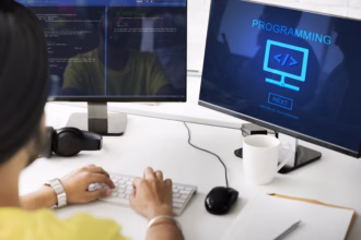 Desenvolvedor programando em uma estação de trabalho com dois monitores, um exibindo linhas de código e outro com a palavra "Programming"