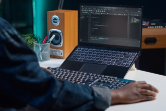 Desenvolvedor programando em laptop em ambiente de trabalho remoto, com editor de código aberto na tela.