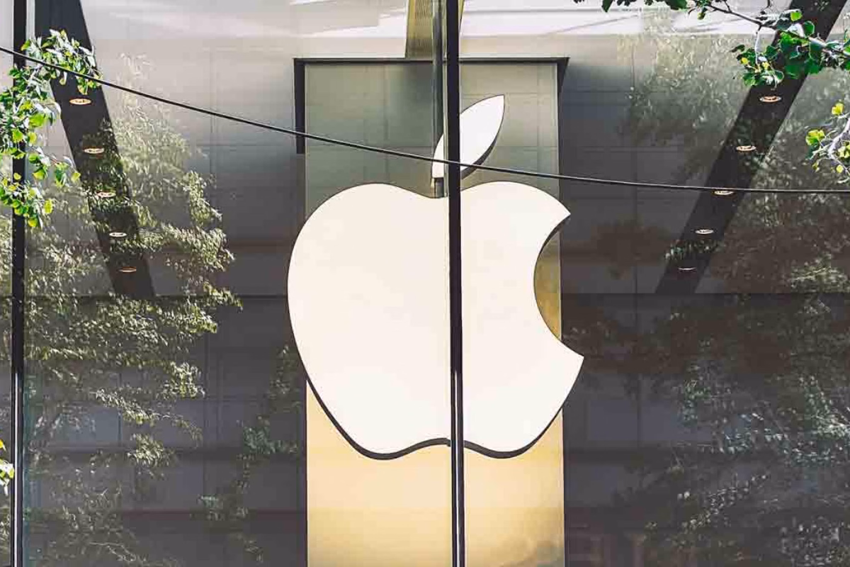Logotipo da Apple em fachada de vidro com reflexo de árvores