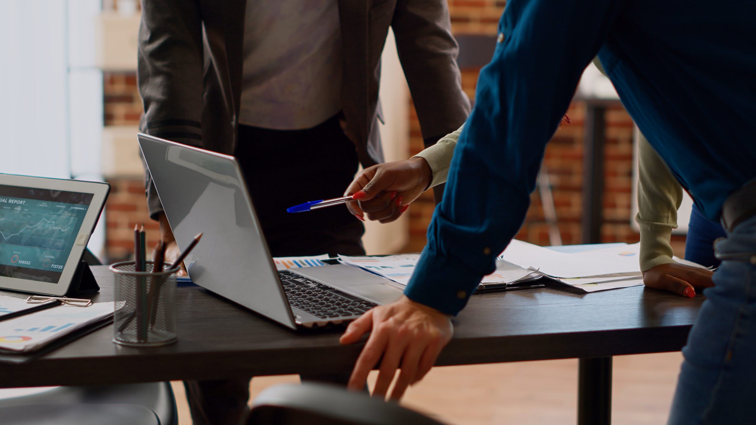 Equipe reunida em volta de um notebook, analisando relatórios e gráficos sobre a mesa.