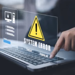 Pessoa tocando o teclado de um notebook com alerta holográfico de "System Error" e triângulo amarelo de aviso sobre a tela